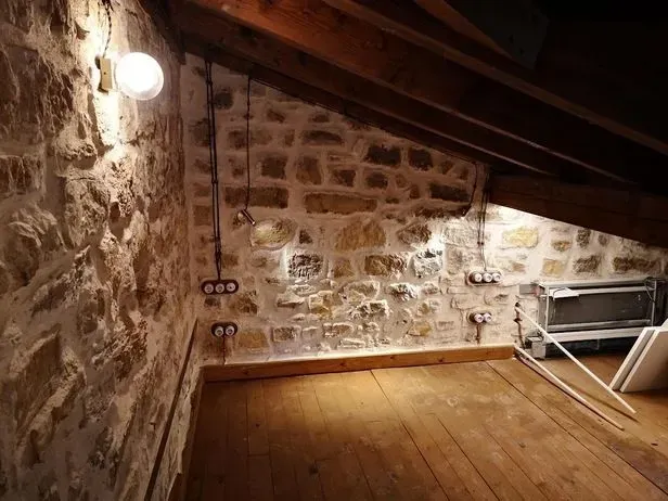 Una habitación con una pared de piedra y un suelo de madera.