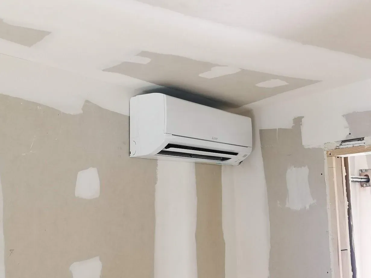 Un acondicionador de aire blanco cuelga del techo de una habitación.