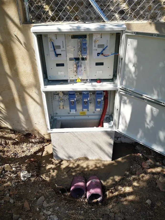 Un par de zapatos están en el suelo al lado de una caja eléctrica.