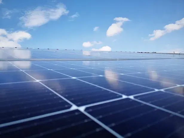 Una fila de paneles solares contra un cielo azul con nubes.