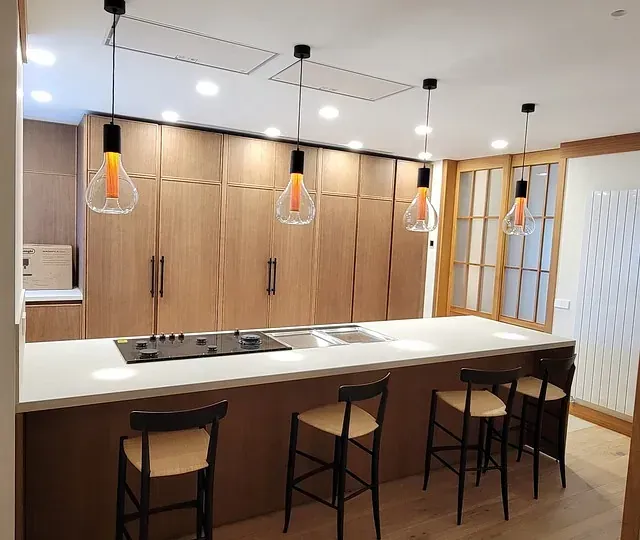 Una cocina con una gran isla y taburetes y un horno de leña.