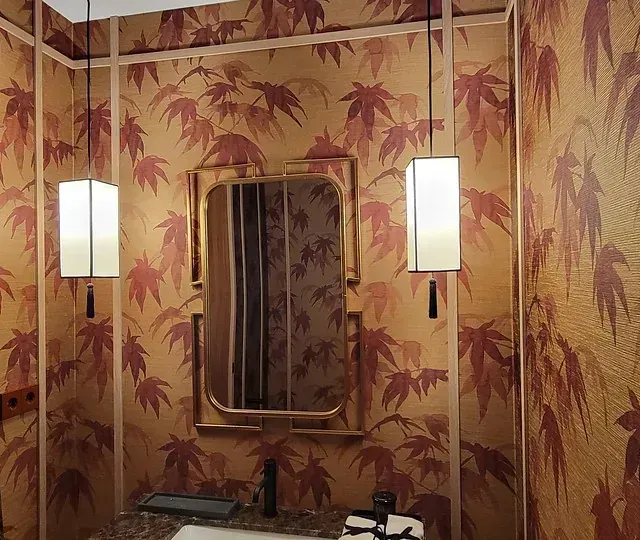 Un baño con un lavabo y un espejo con hojas en la pared.