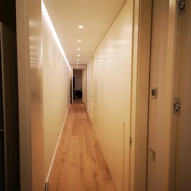 Un largo pasillo con suelos de madera y paredes blancas.