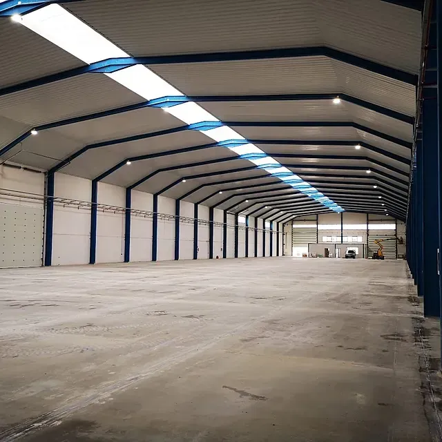 Un gran almacén vacío con techo azul y suelo de hormigón.