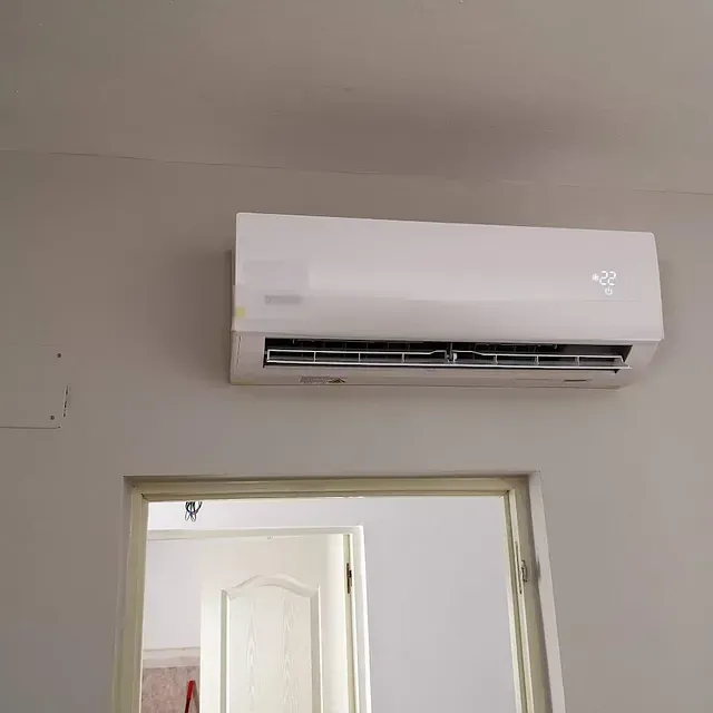 Un acondicionador de aire blanco está montado en la pared al lado de una puerta.