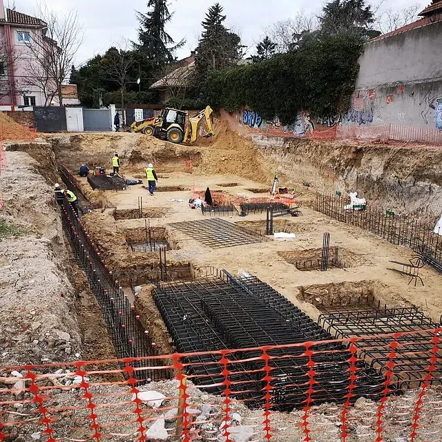 Un sitio de construcción con una excavadora amarilla al fondo
