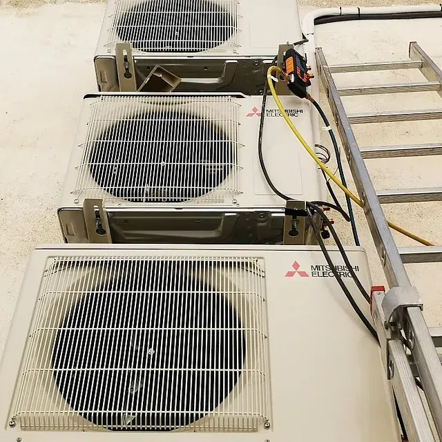 Tres aparatos de aire acondicionado Mitsubishi están alineados junto a una escalera.
