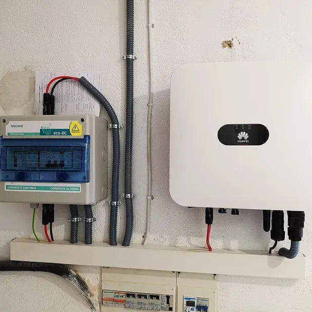 Un panel solar está montado en una pared al lado de una caja de fusibles.