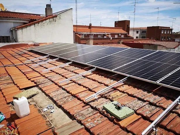 Una fila de paneles solares están colocados encima de un techo de tejas.