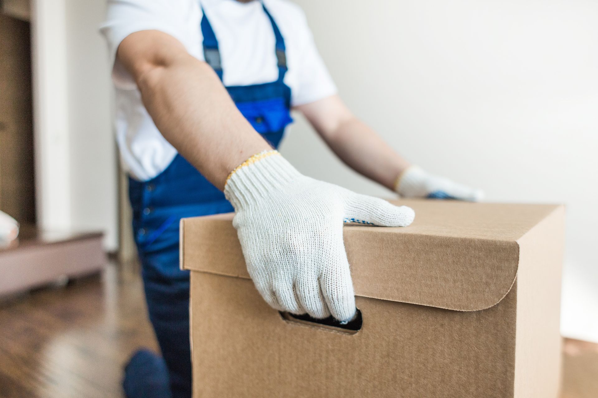 Un déménageur aux gants blancs portant un carton