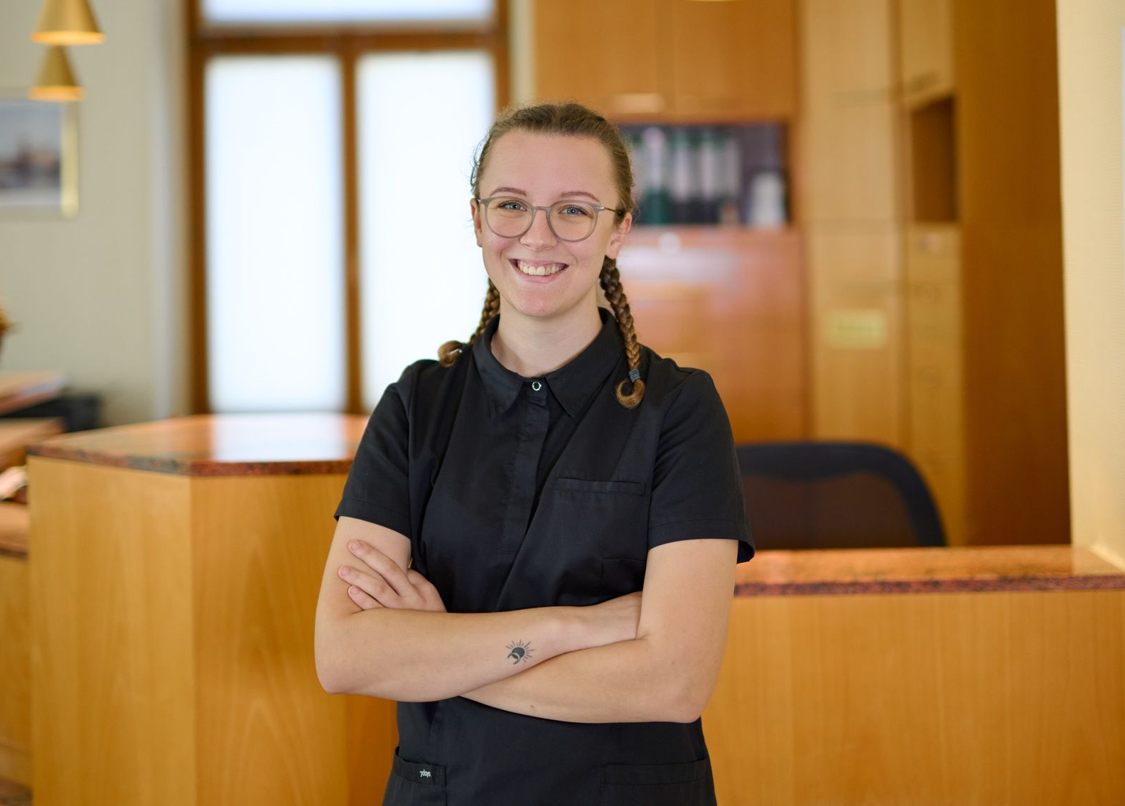 Eine Frau steht mit verschränkten Armen vor einer Theke.