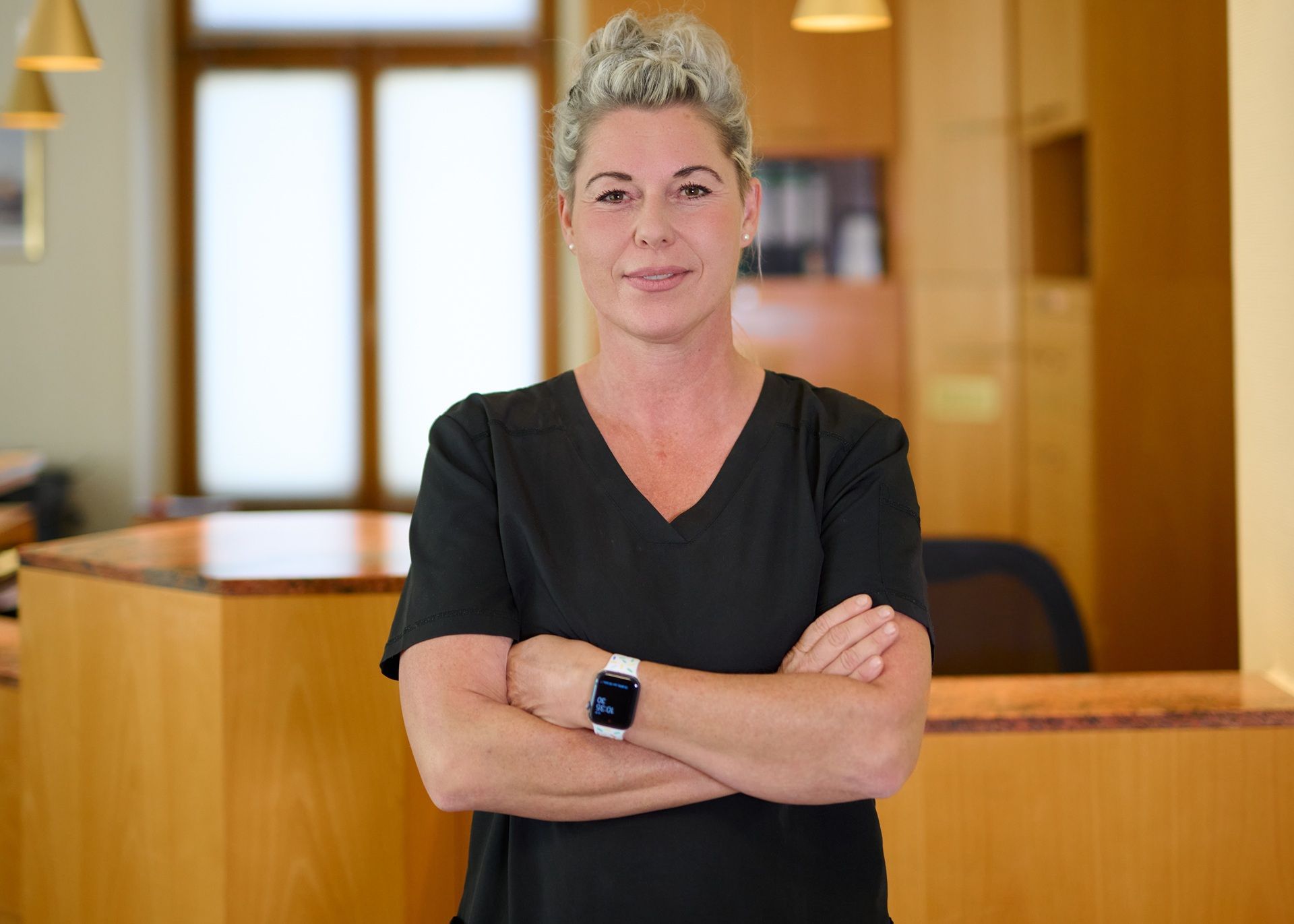 Eine Frau steht mit verschränkten Armen vor einer Theke.