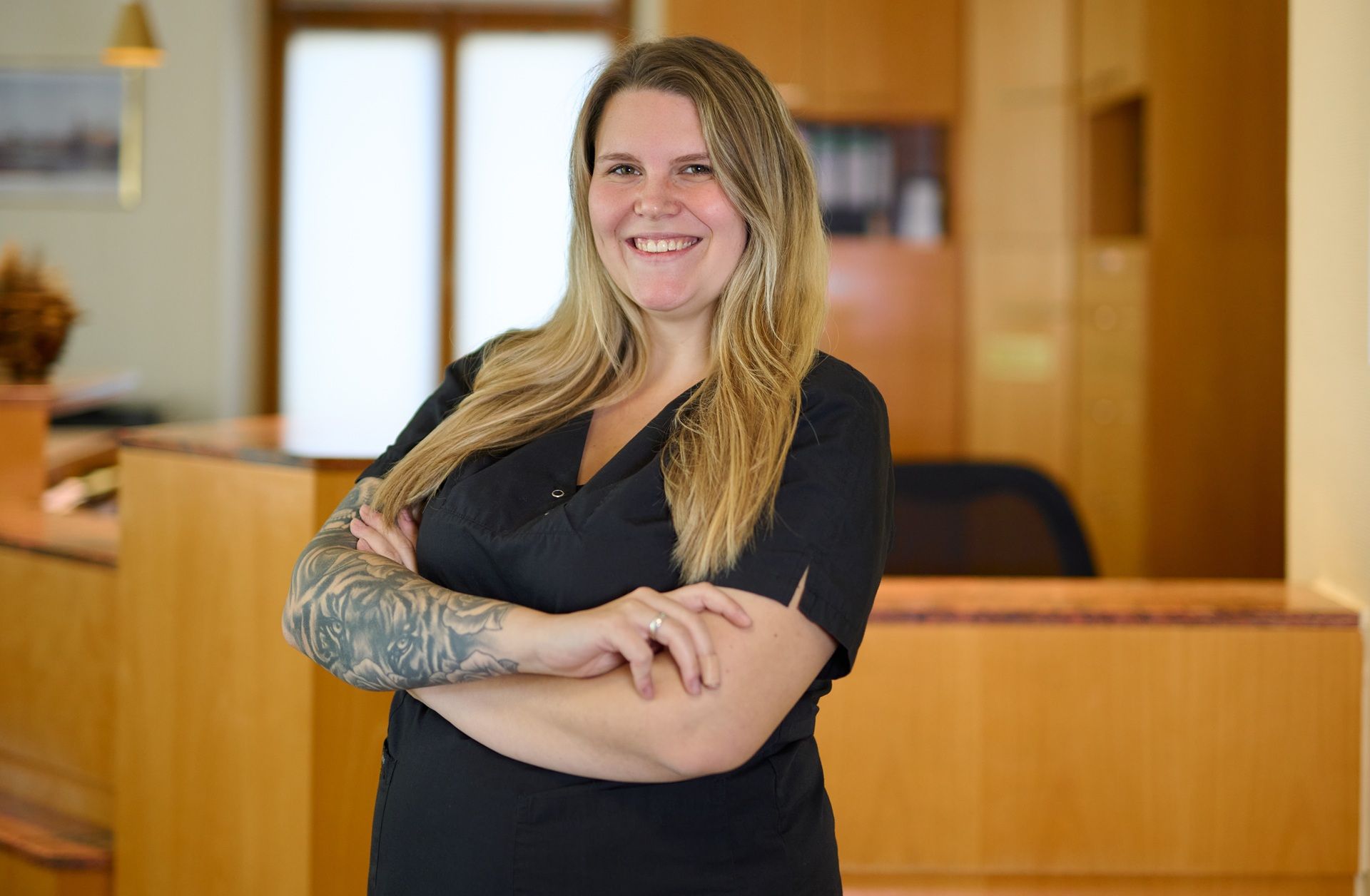 Eine Frau mit verschränkten Armen vor einem Holztresen