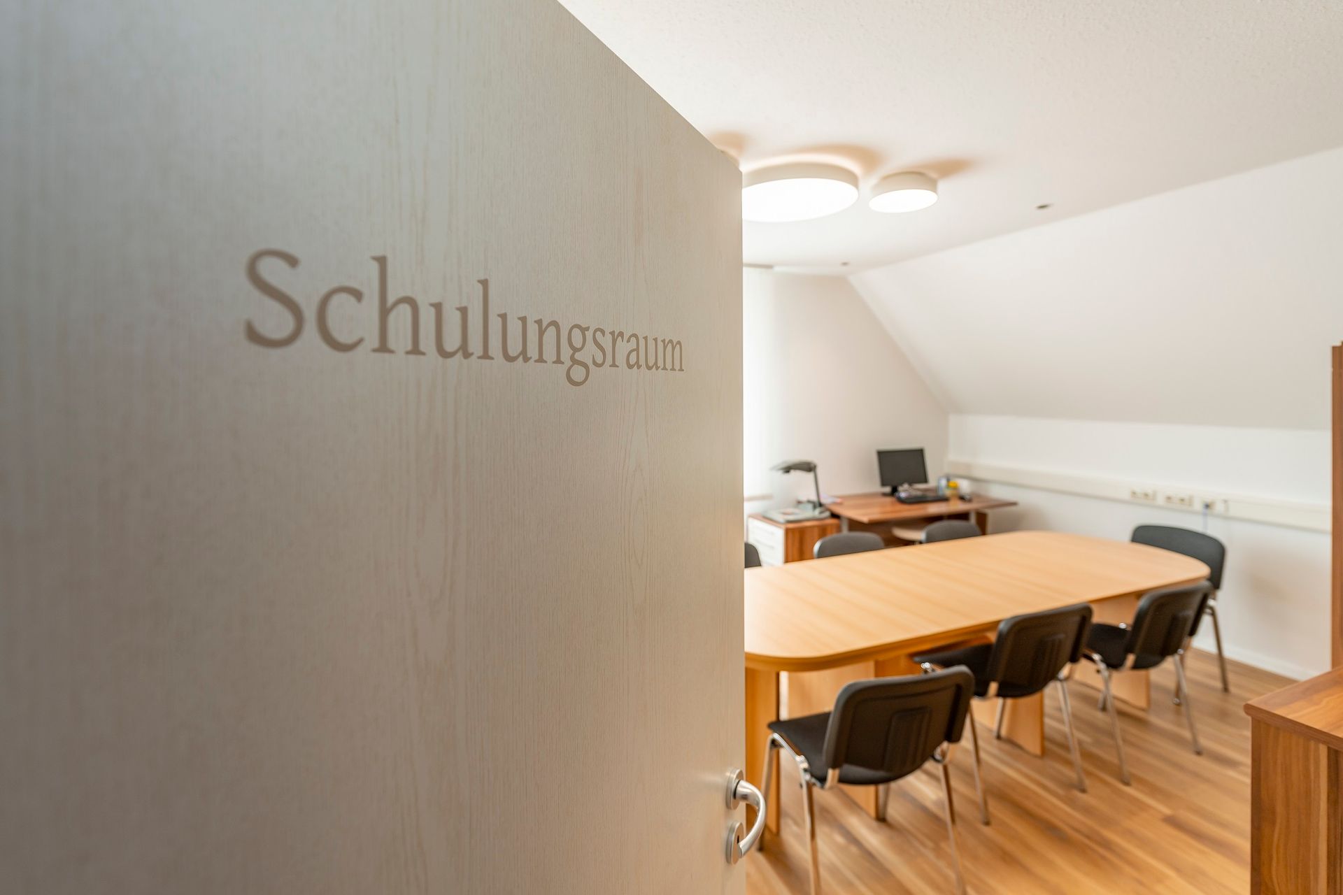 Ein Raum mit einem Tisch und Stühlen und einer Tür mit der Aufschrift „Schulungsraum“