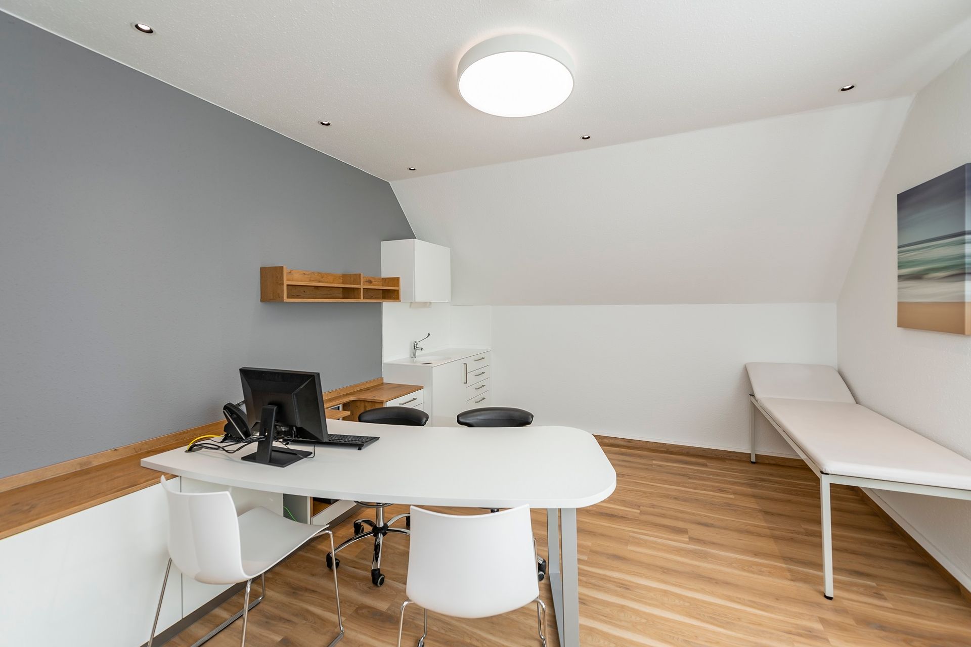 Eine Arztpraxis mit Schreibtisch, Stühlen und Couch.