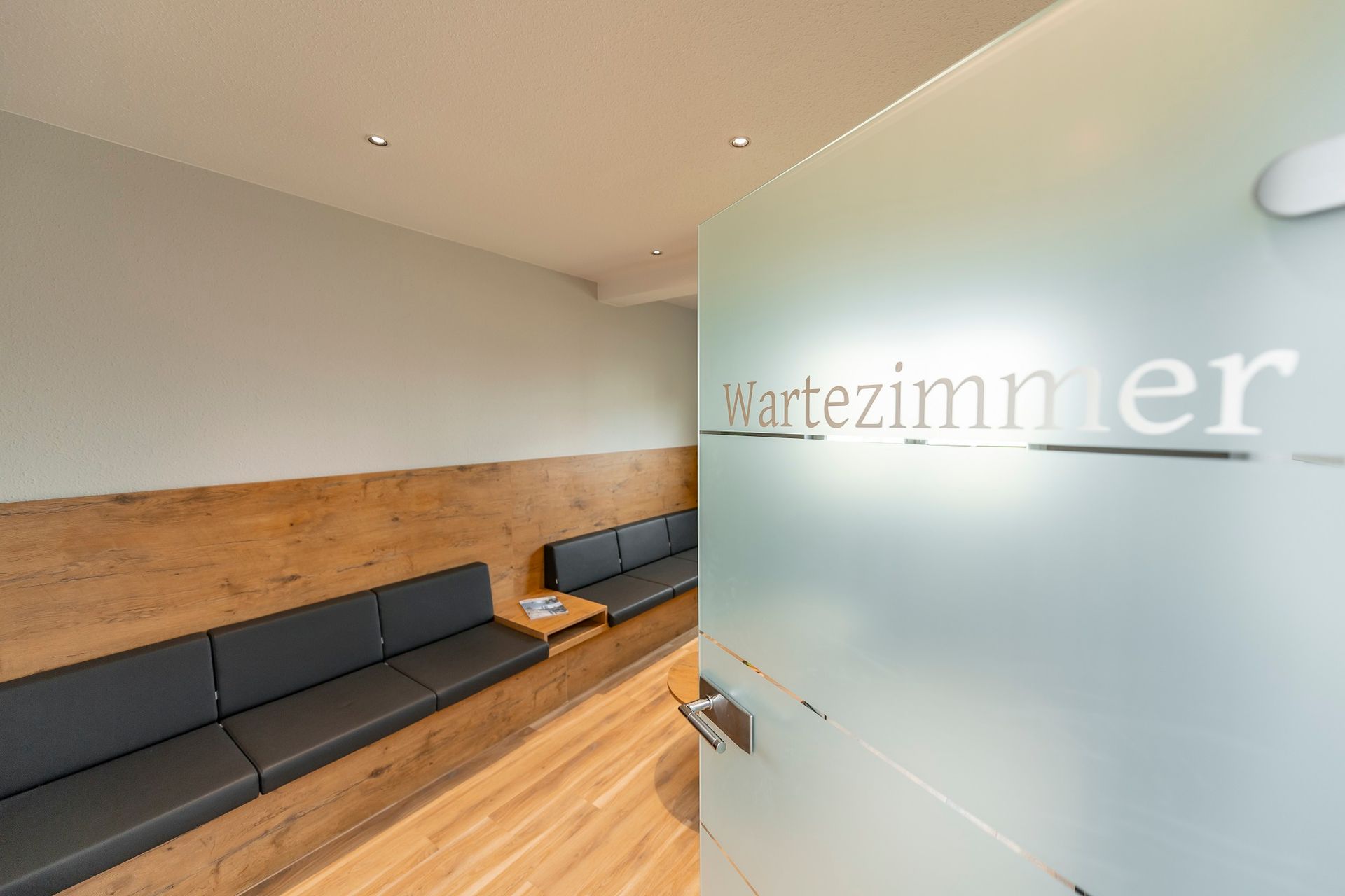 Ein Wartezimmer mit Glastür und Couch.