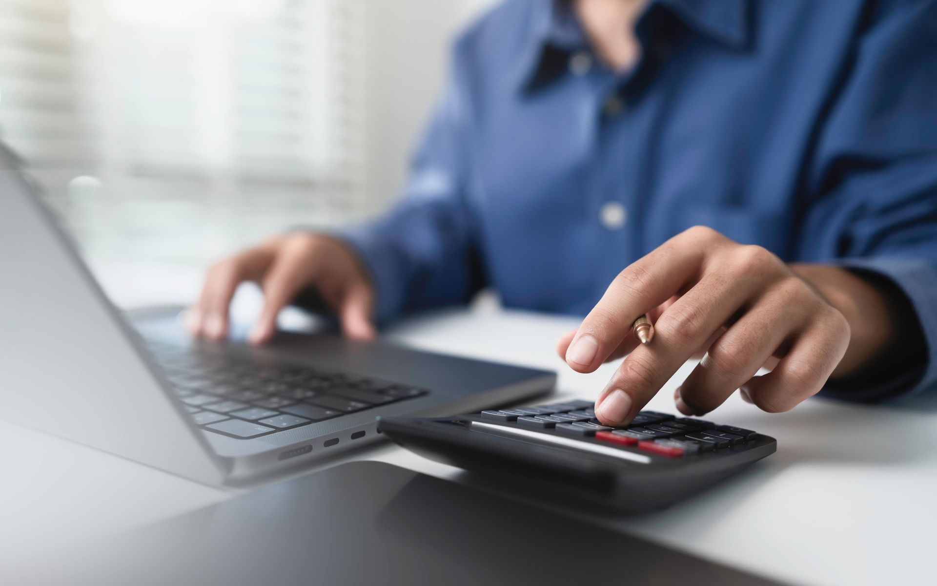 Personne utilisant une calculatrice, un ordinateur portable, et analysant les finances.