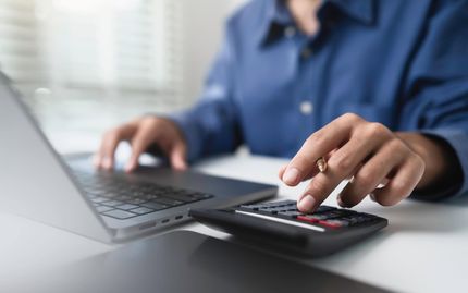 Personne utilisant une calculatrice, un ordinateur portable, et analysant les finances.