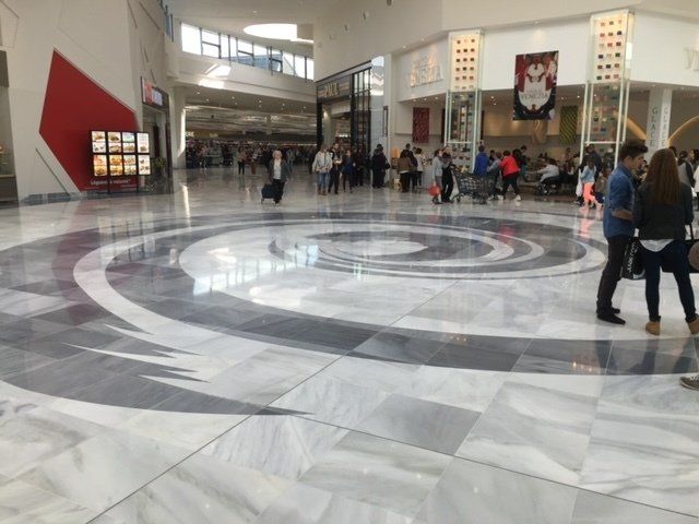 Hall d'entrée spacieux avec un grand sol circulaire en marbre, les gens étant rassemblés au fond et sur le côté droit.