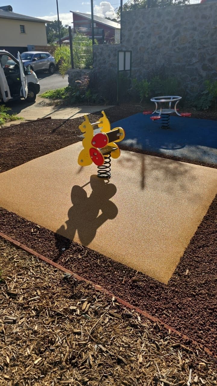 Une toupie jaune sur un tapis beige dans une cour ensoleillée
