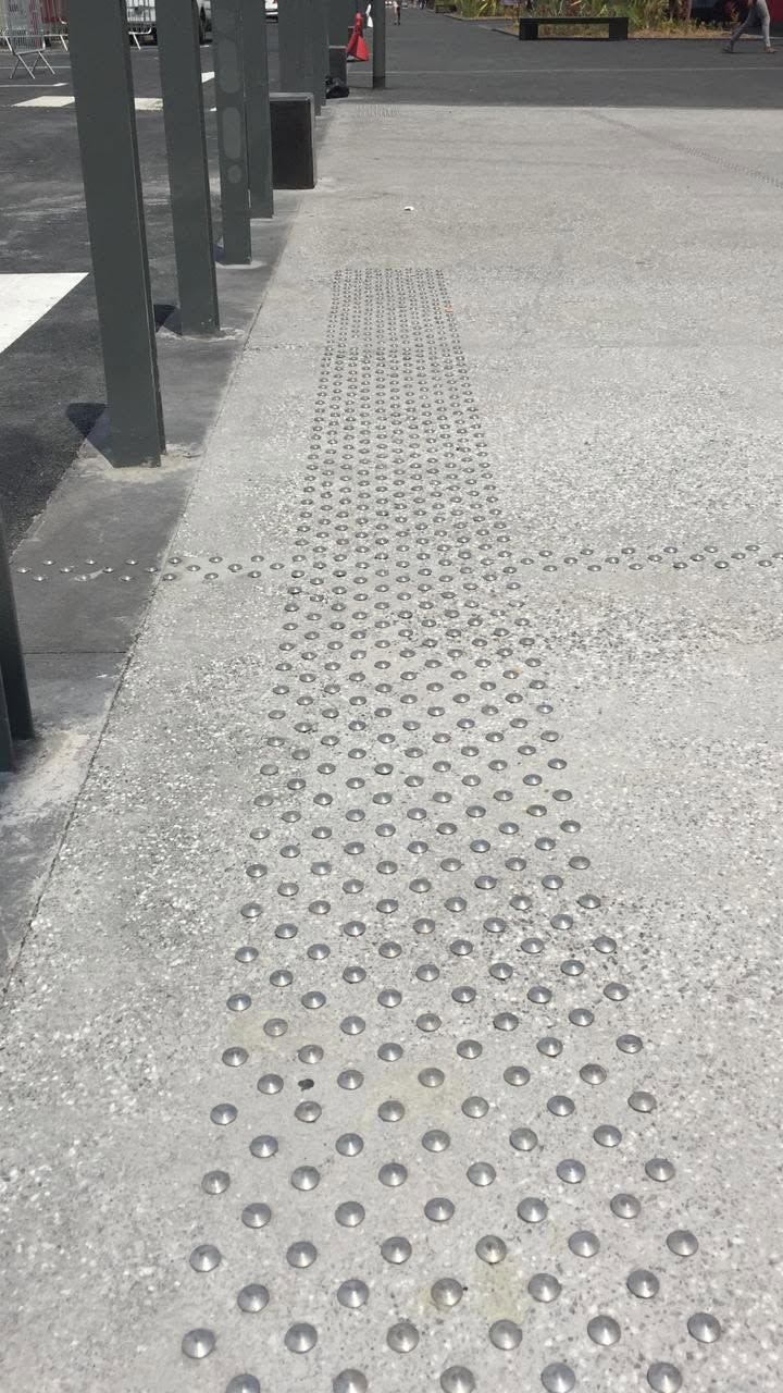 Bande de pavage podotactile sur sol gris