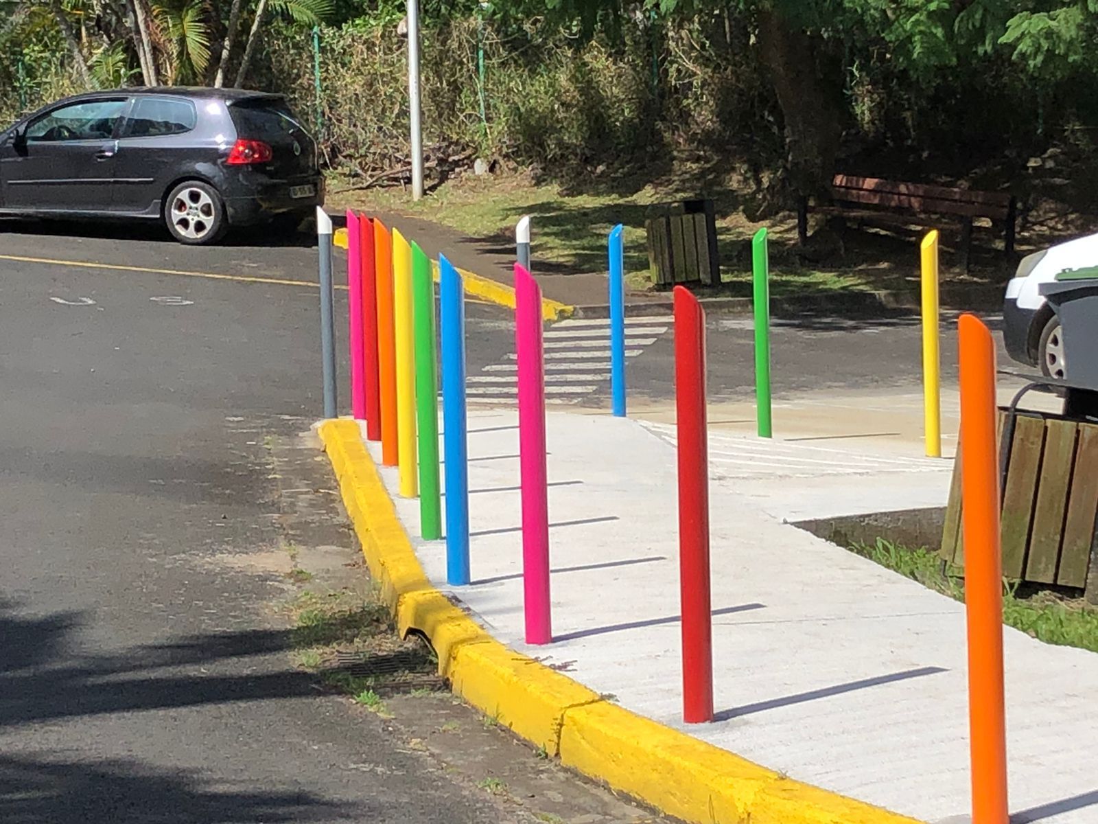 Des potelets colorées bordent un trottoir 