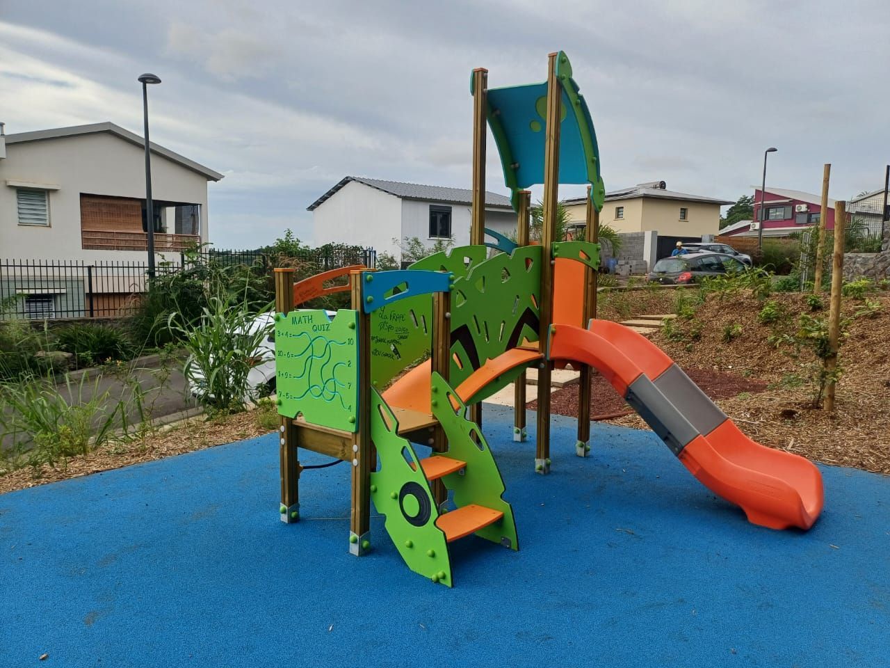 Toboggan et structure d'escalade colorés sur une surface en caoutchouc bleu dans une cour résidentielle