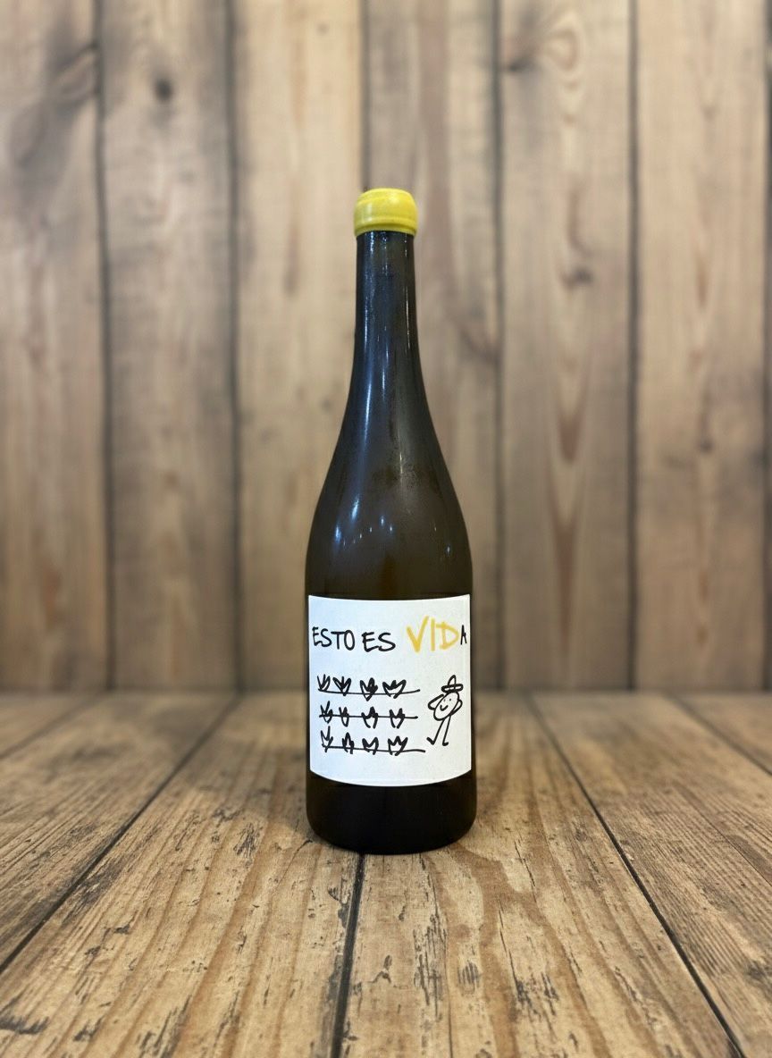 Botella de vino con tapón amarillo y etiqueta escrita a mano sobre superficie de madera.