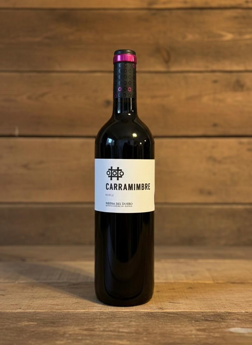 Botella de vino tinto con etiqueta blanca, sobre superficie de madera, con fondo de madera.