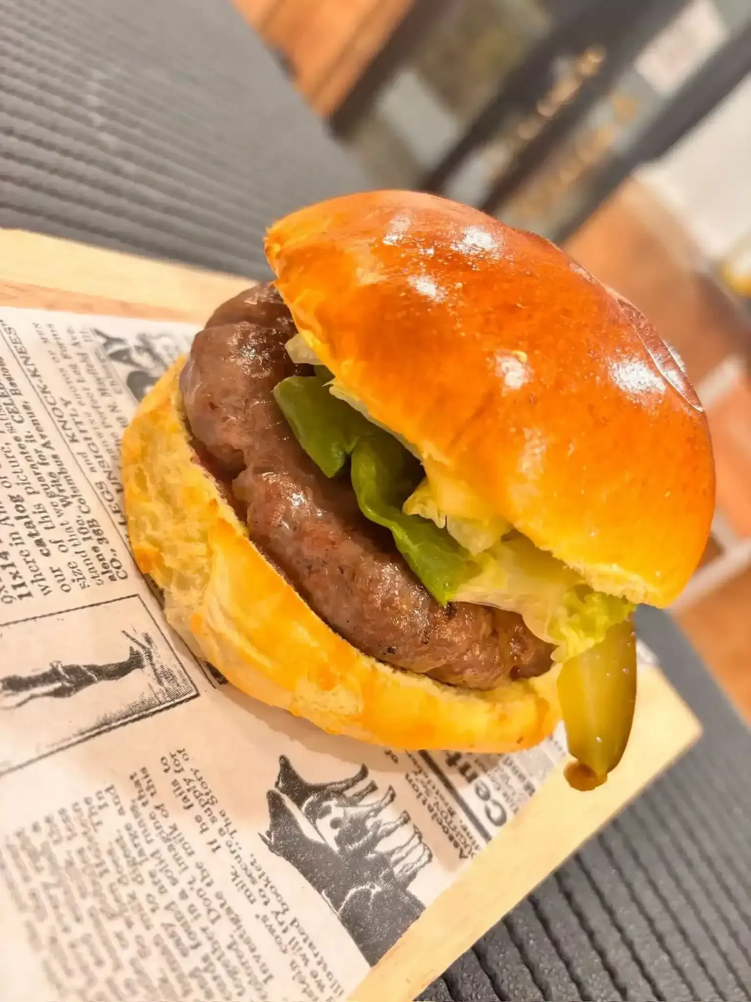 Hamburguesa con pan brioche, carne, lechuga y pepinillo en una tabla de madera.