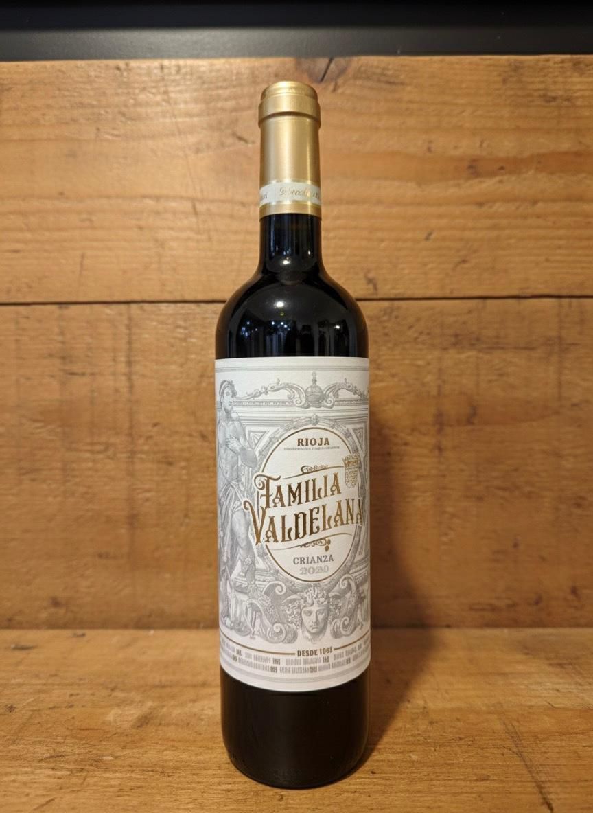 Botella de vino con etiqueta blanca y dorada sobre fondo de madera.