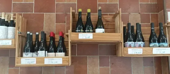 Estanterías de madera con botellas de vino expuestas contra una pared de ladrillo.