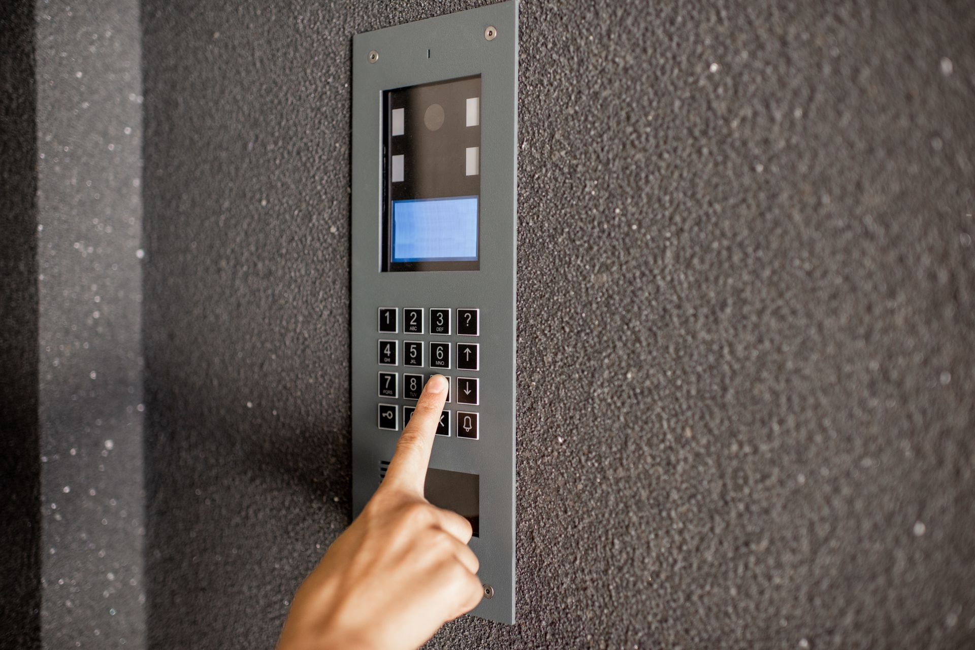 Une personne appuie sur les boutons d'un interphone moderne.