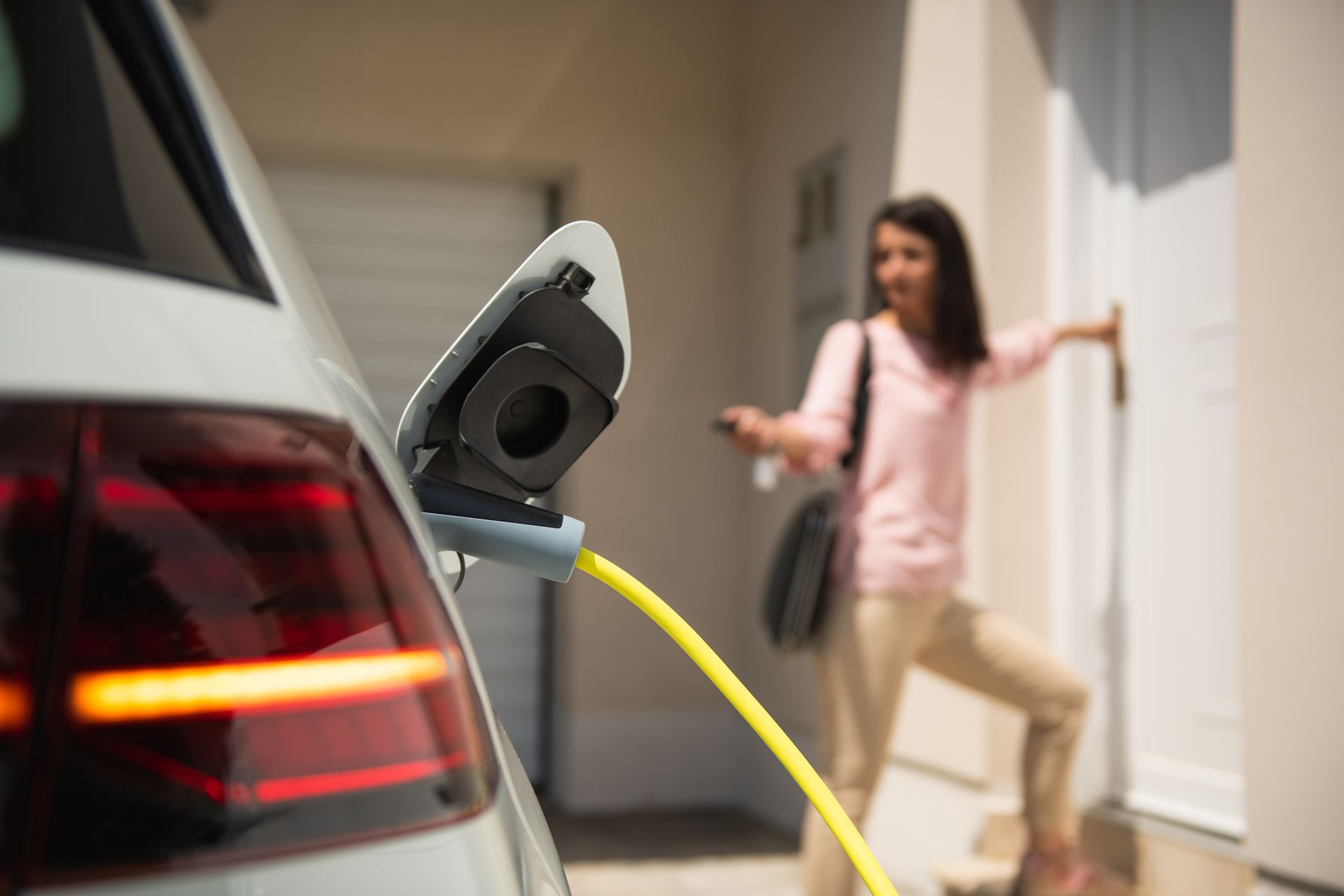 Voiture électrique en charge devant l'entrée d'une maison individuelle.