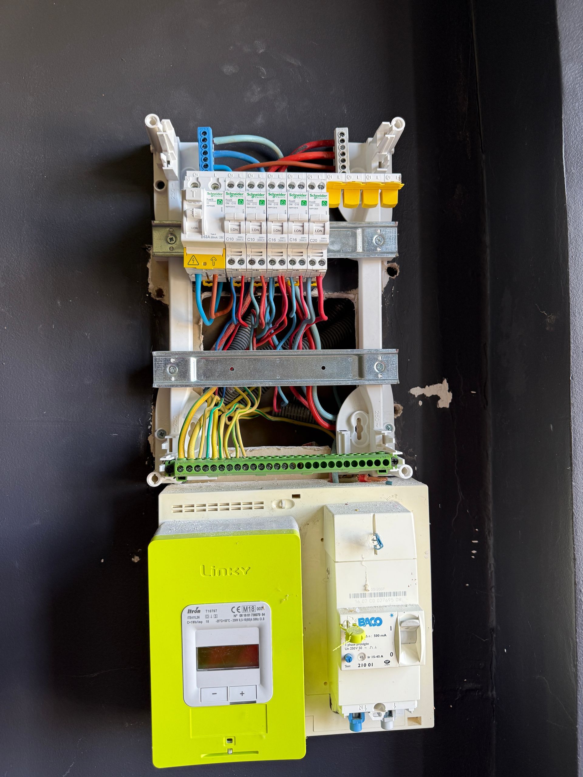 Tableau électrique résidentiel comprenant un compteur Linky, un disjoncteur de branchement et plusieurs protections modulaires.