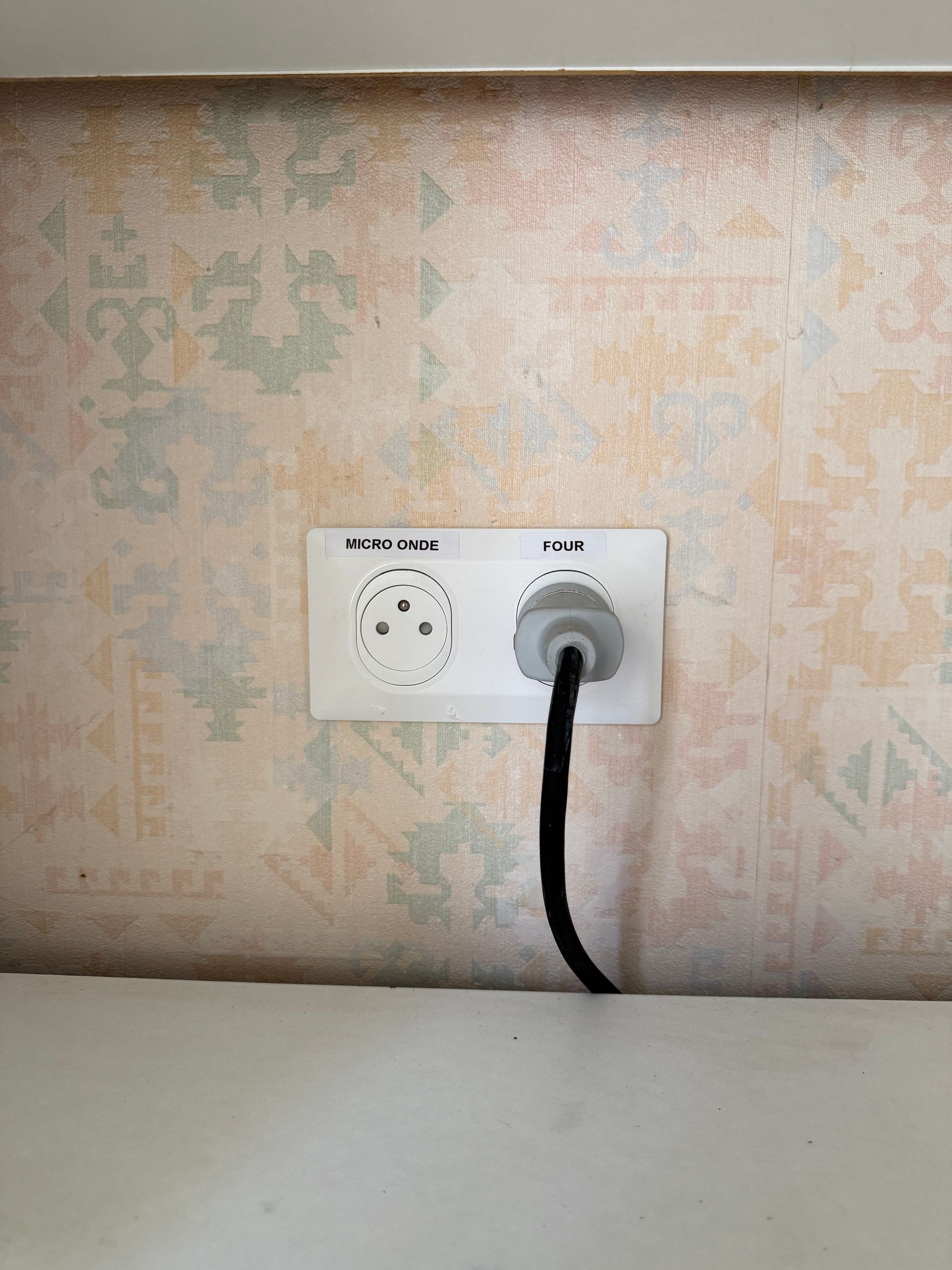 Deux prises murales sur lesquelles sont collées des étiquettes Micro-ondes et Four.