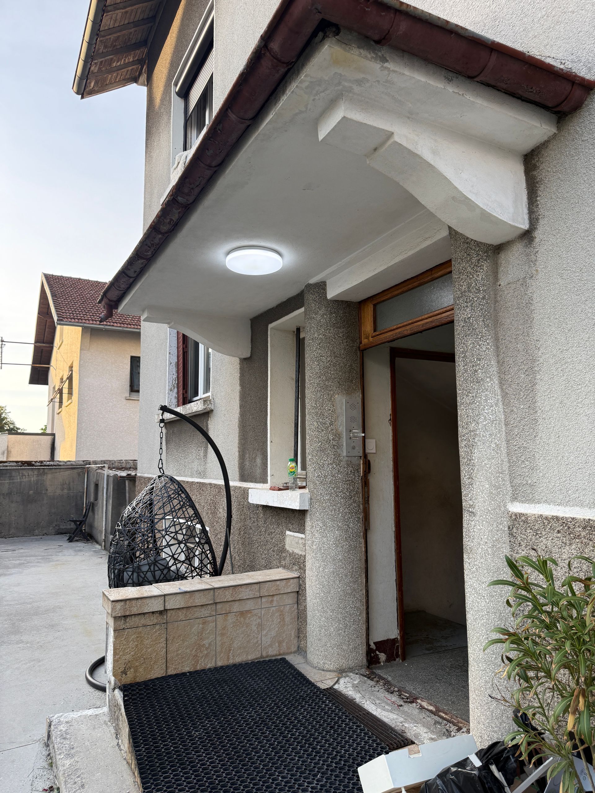 Entrée de maison avec éclairage extérieur intégré dans une marquise de porte.