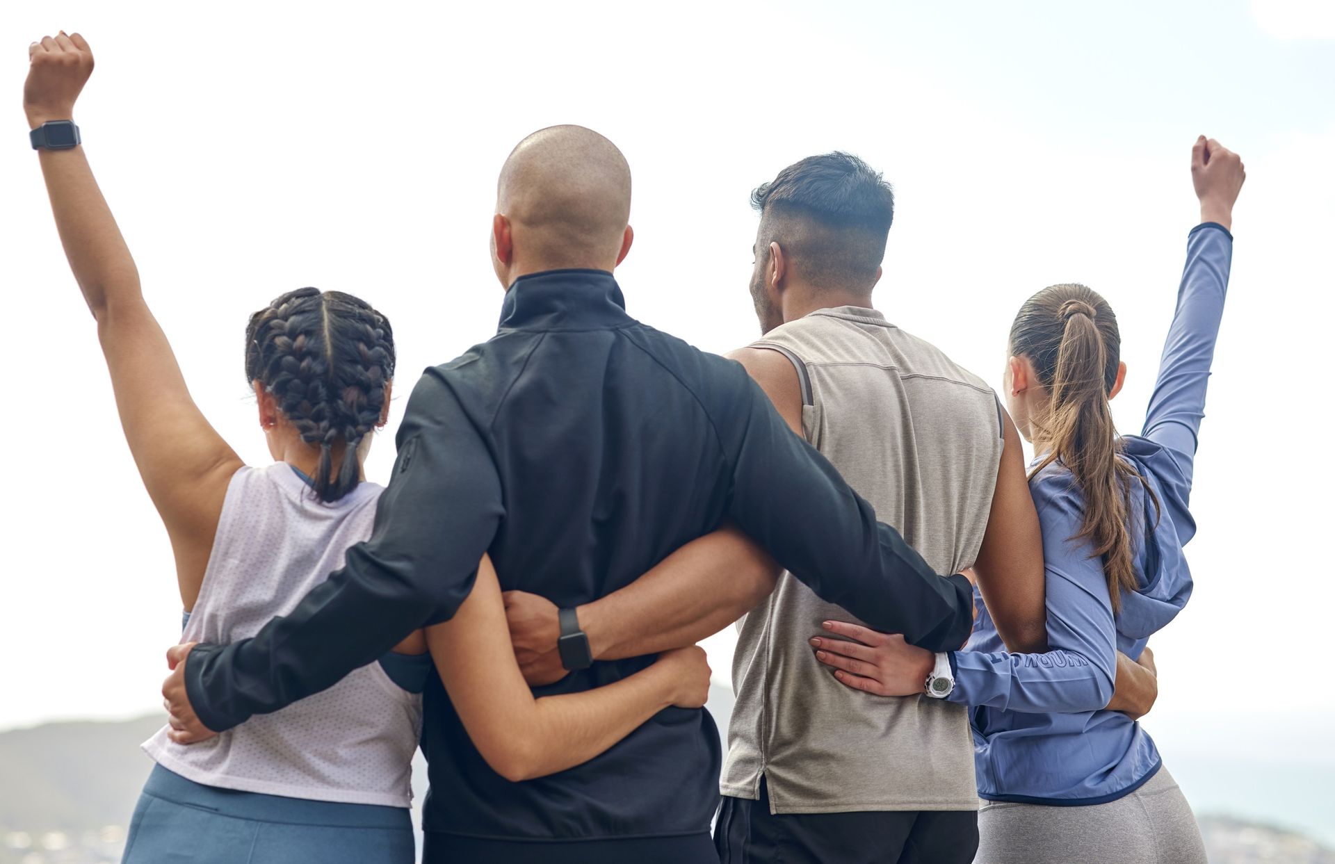 Cuatro personas abrazadas, mirando una vista con los brazos levantados en señal de celebración.