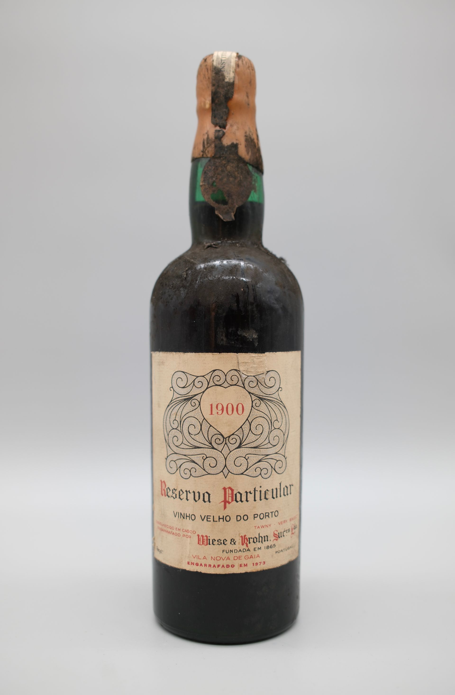 Une bouteille de vin Reserva Partidor de 1906, avec une étiquette et un bouchon abîmés par le temps.