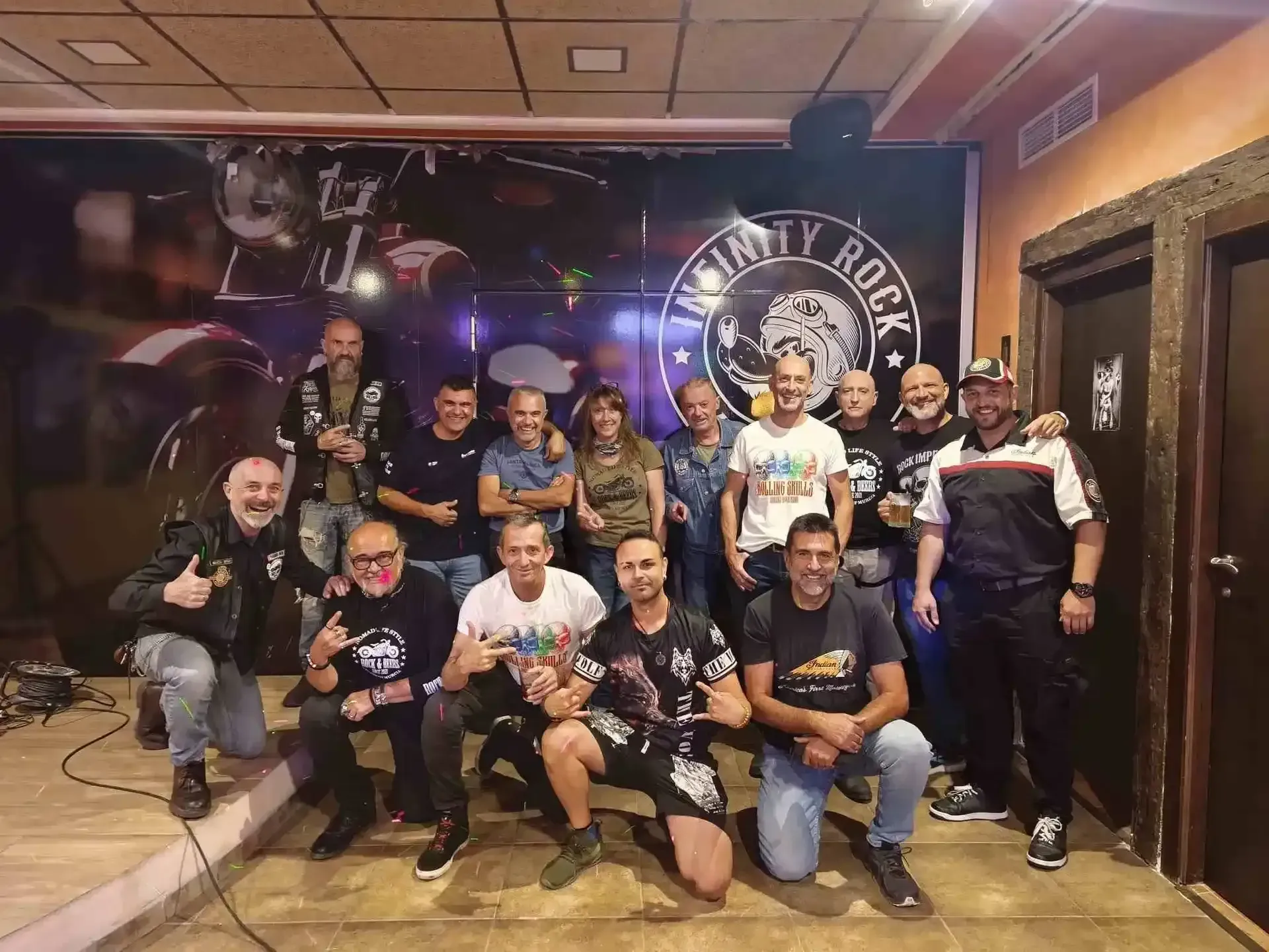 Un grupo de personas posa en un bar con un fondo de motos. Algunos sonríen, otros levantan el pulgar.
