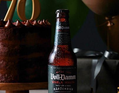 Botella de cerveza Voll-Damm delante de una tarta de chocolate con un 70 encima.