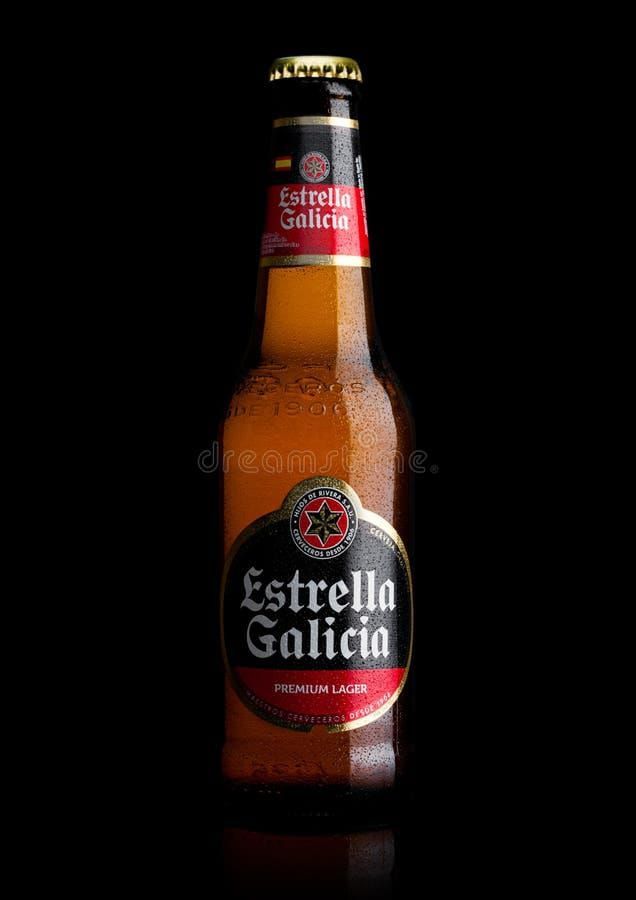 Botella de cerveza Estrella Galicia con etiqueta roja y negra sobre fondo negro.