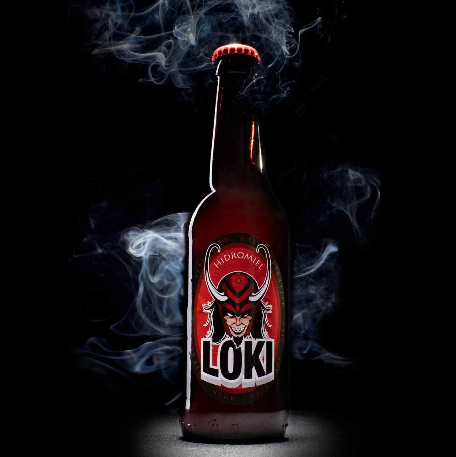 Botella de cerveza Loki con una etiqueta roja con la imagen de Loki; rodeada de humo sobre un fondo negro.