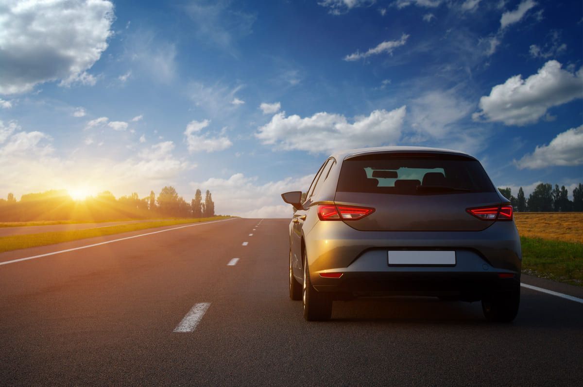 Un coche circula por una carretera al atardecer.