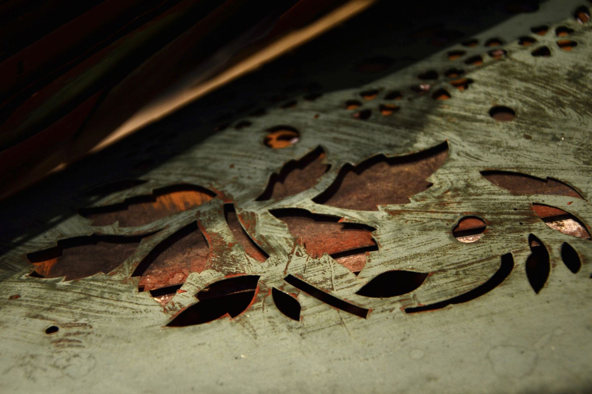 Nahaufnahme einer dekorativen Metallarbeit mit ausgeschnittenem Blattdesign, das eine darunter liegende kupferfarbene Schicht freigibt.