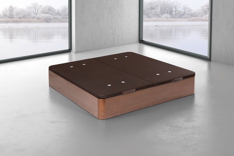 Una otomana marrón está sentada en una habitación al lado de una ventana.