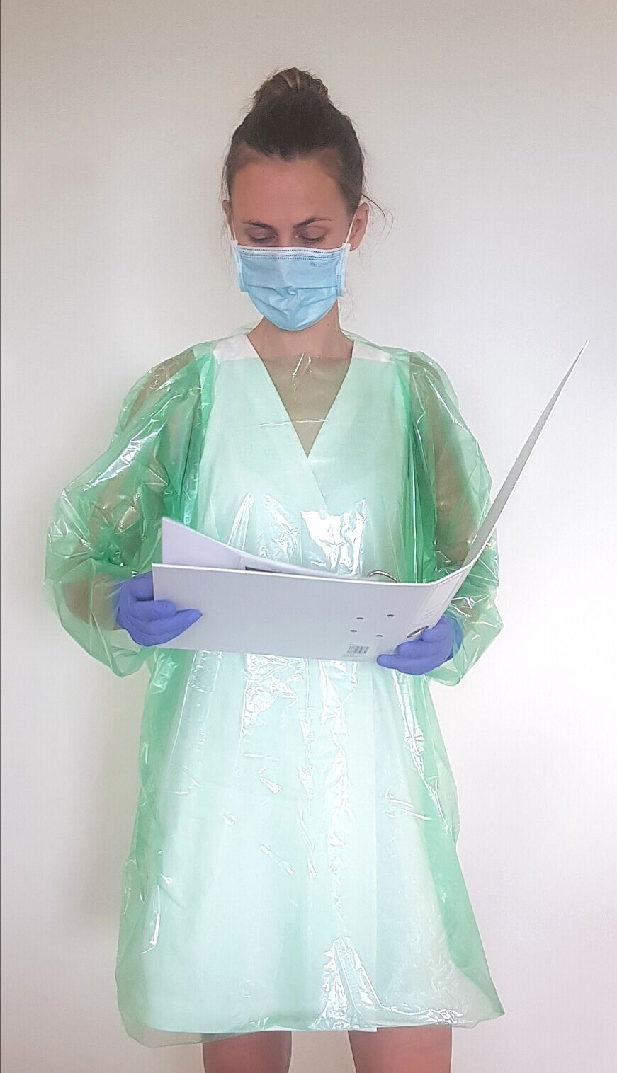 Una mujer que lleva una máscara y guantes sostiene un trozo de papel.