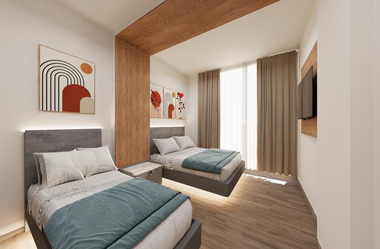 A bedroom with two beds and a television on the wall.
