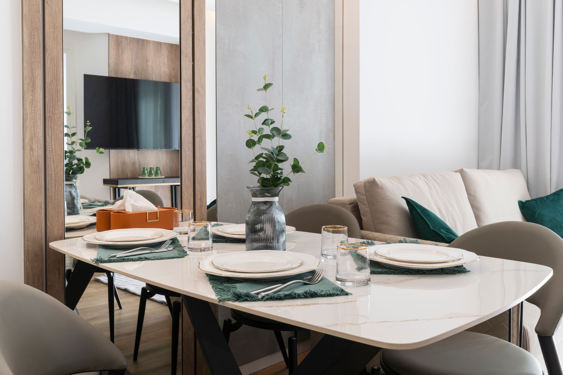 Dining area with a marble table set for a meal, mirror, and a sofa.