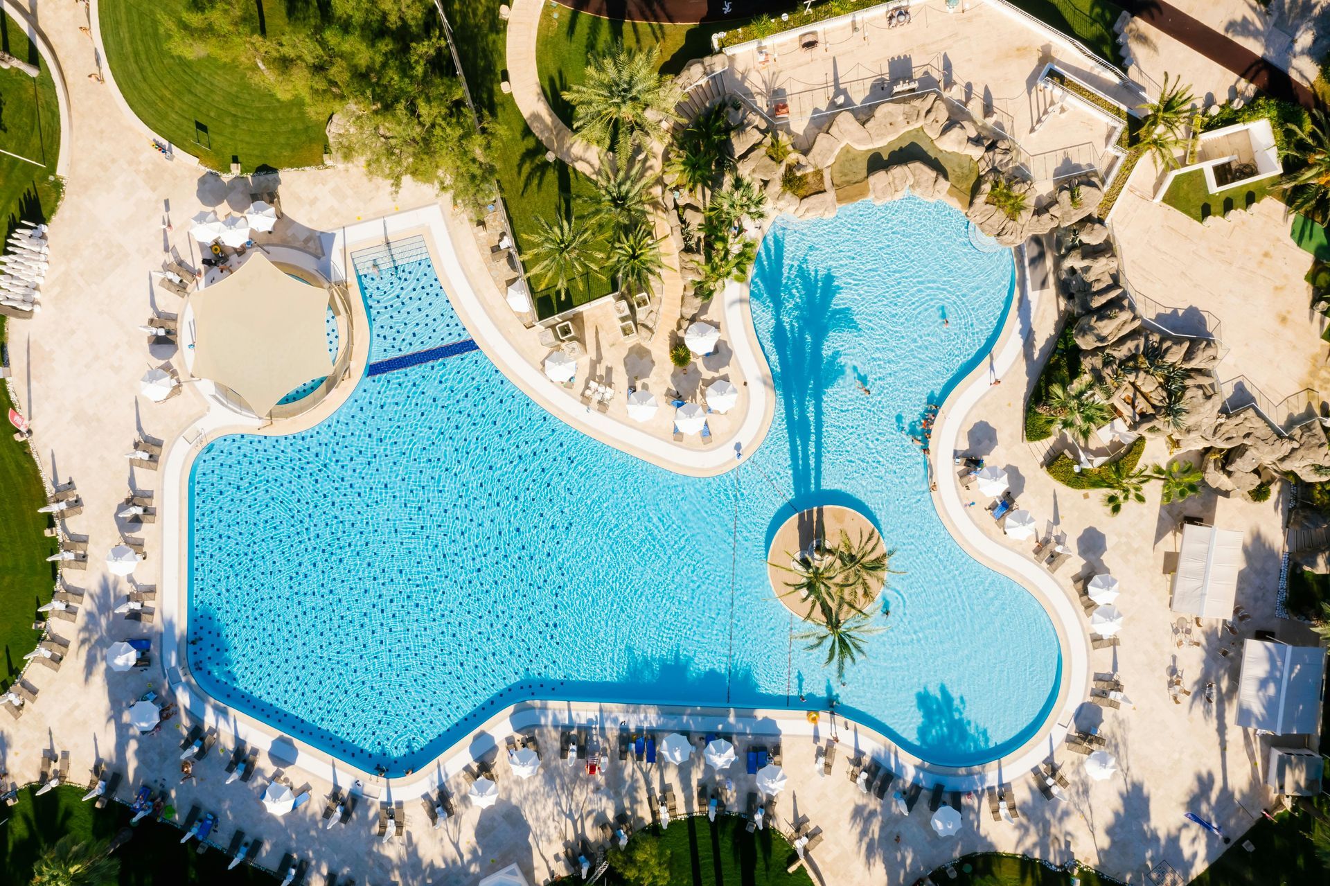 An aerial view of a large swimming pool surrounded by palm trees.